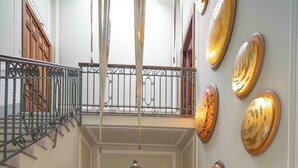 A spacious hallway with a central light fixture, a staircase, and decorative wall art.