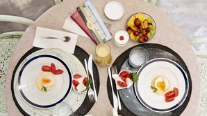 A round dining table with plates, cutlery, and a bowl of fruit.