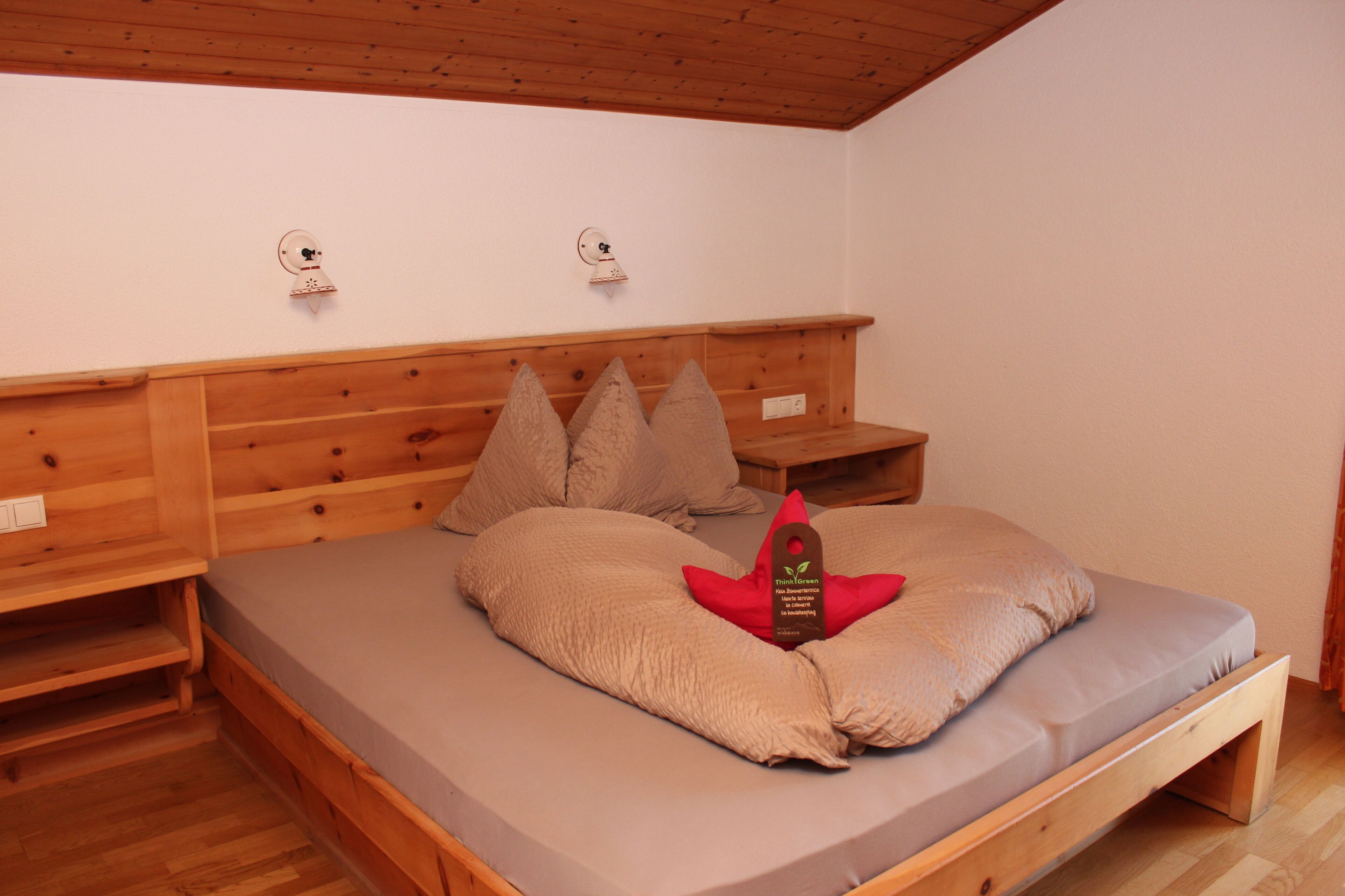 A wooden bed with a mattress, pillows, and a tag on the pillow.