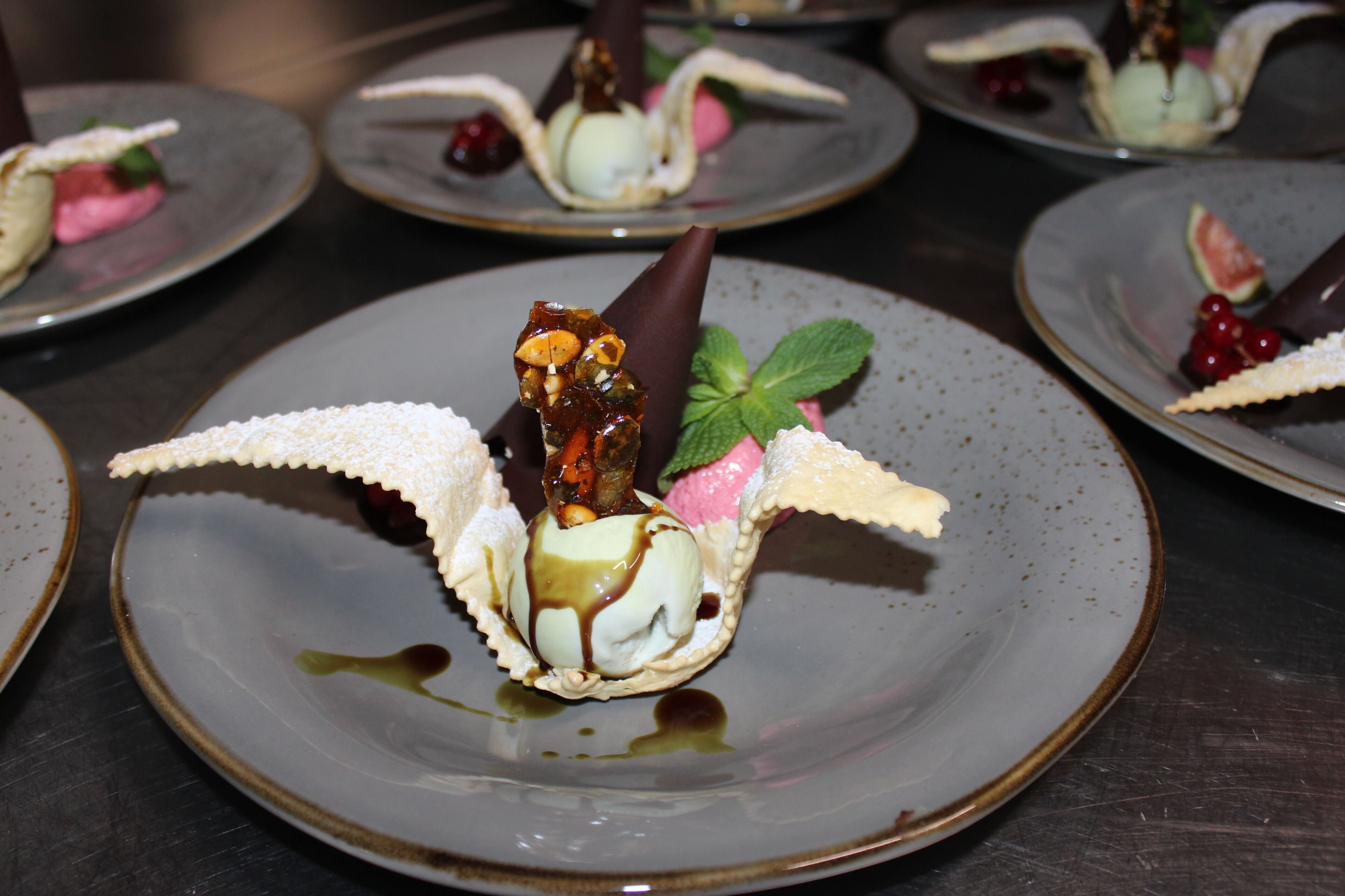 Un piattino con una pallina di gelato, un cono al cioccolato e guarnizioni.