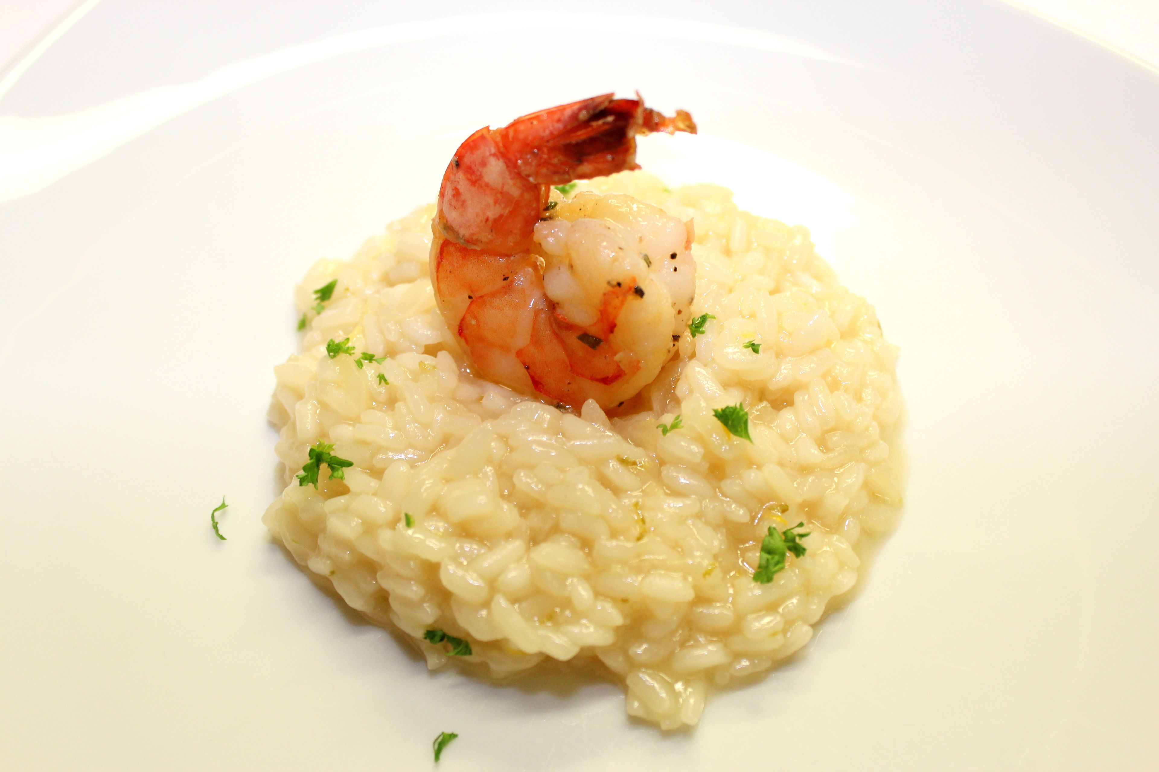 Un plato de risotto con camarones y adornado con hierbas.