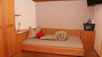 Un lit en bois avec un matelas, des oreillers, une lampe et un panier.