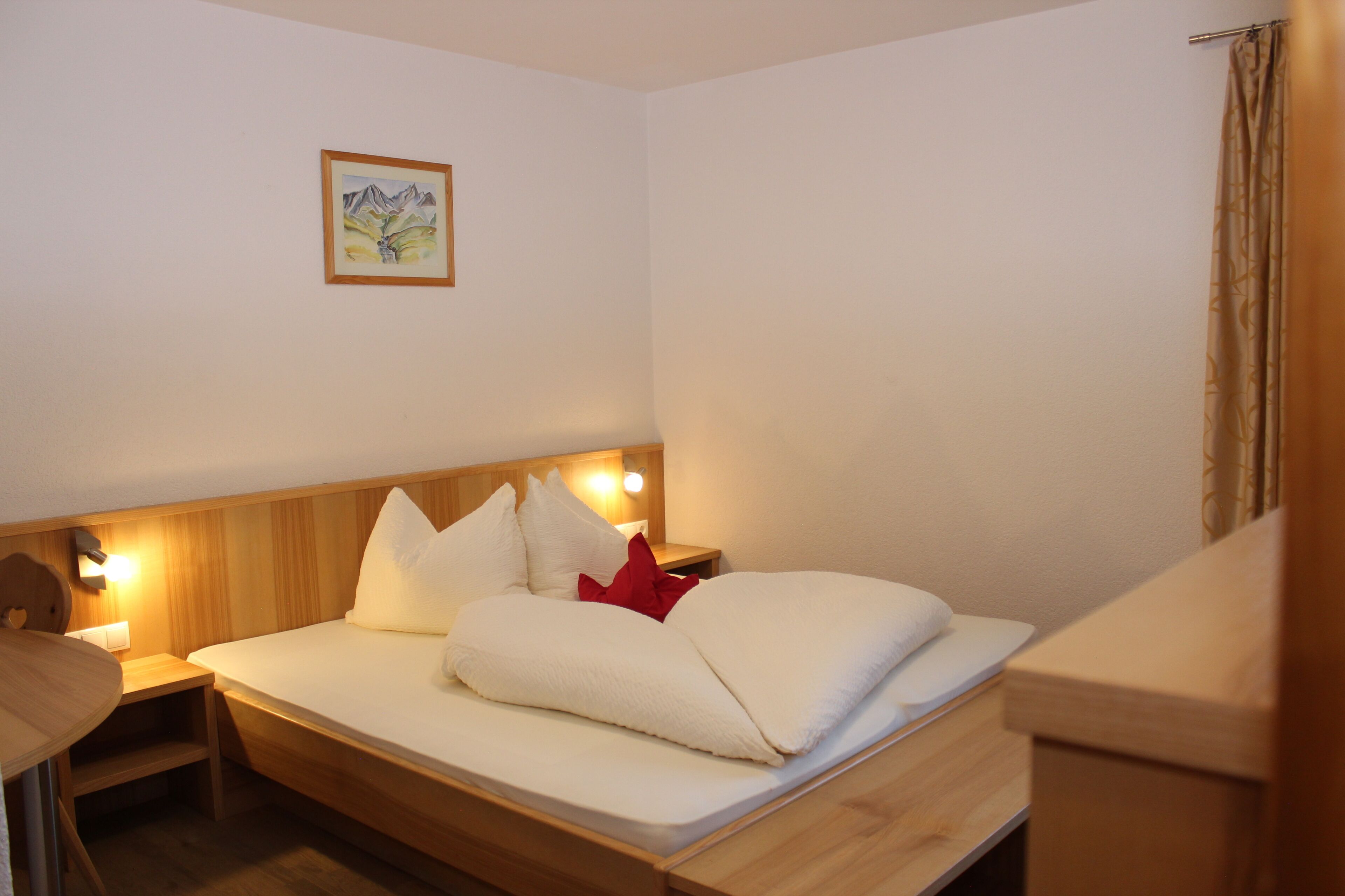 Ein Einzelbett mit Holz-Kopfteil, einem Nachttisch und einer Wandleuchte.