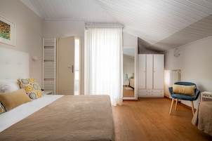 A bedroom with a bed, a chair, a wardrobe, and a mirror.