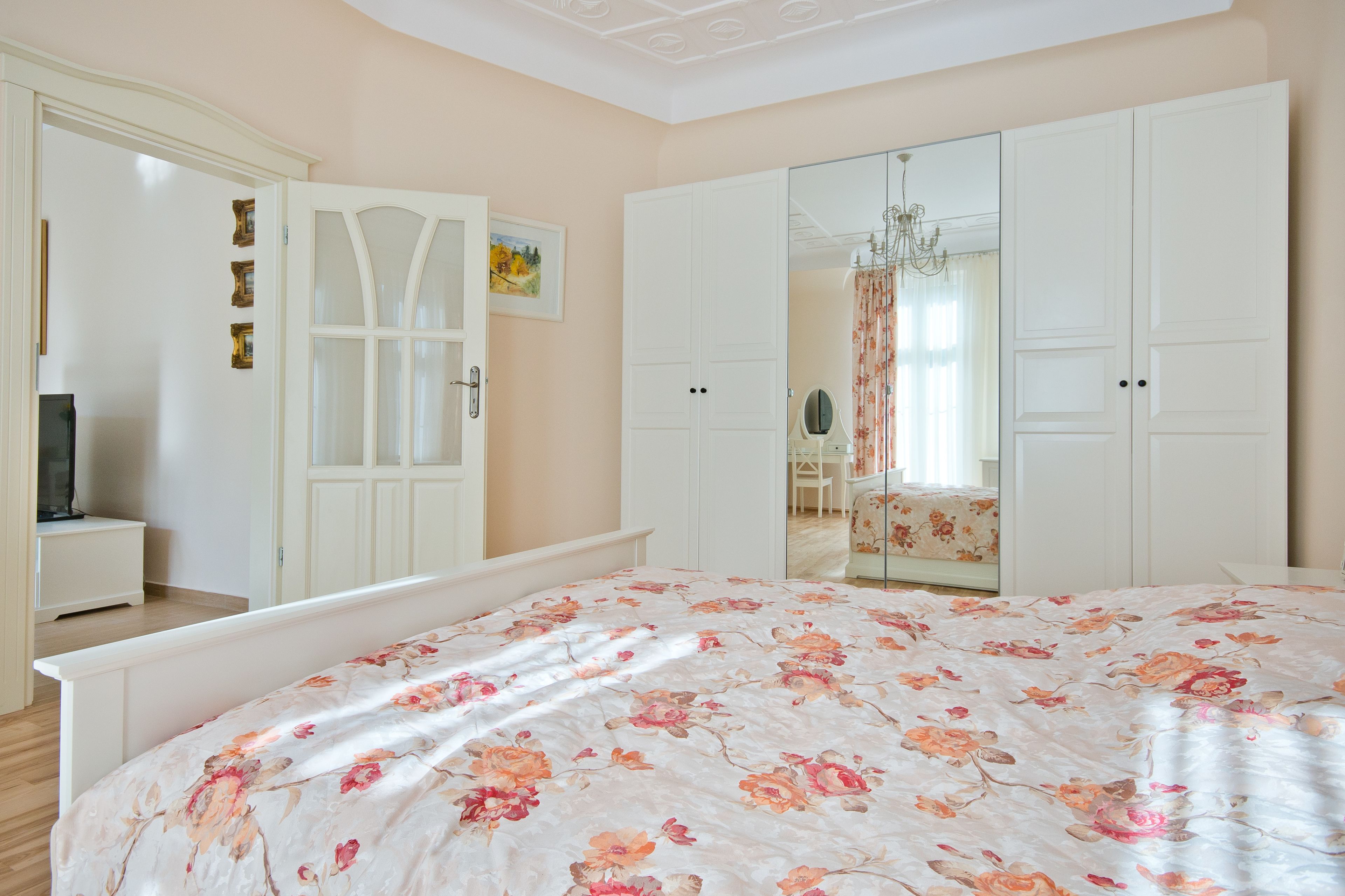 A bedroom with a large bed, a wardrobe, a mirror, and a dresser.