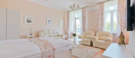 A bedroom with a bed, two chairs, a small table, and a TV.