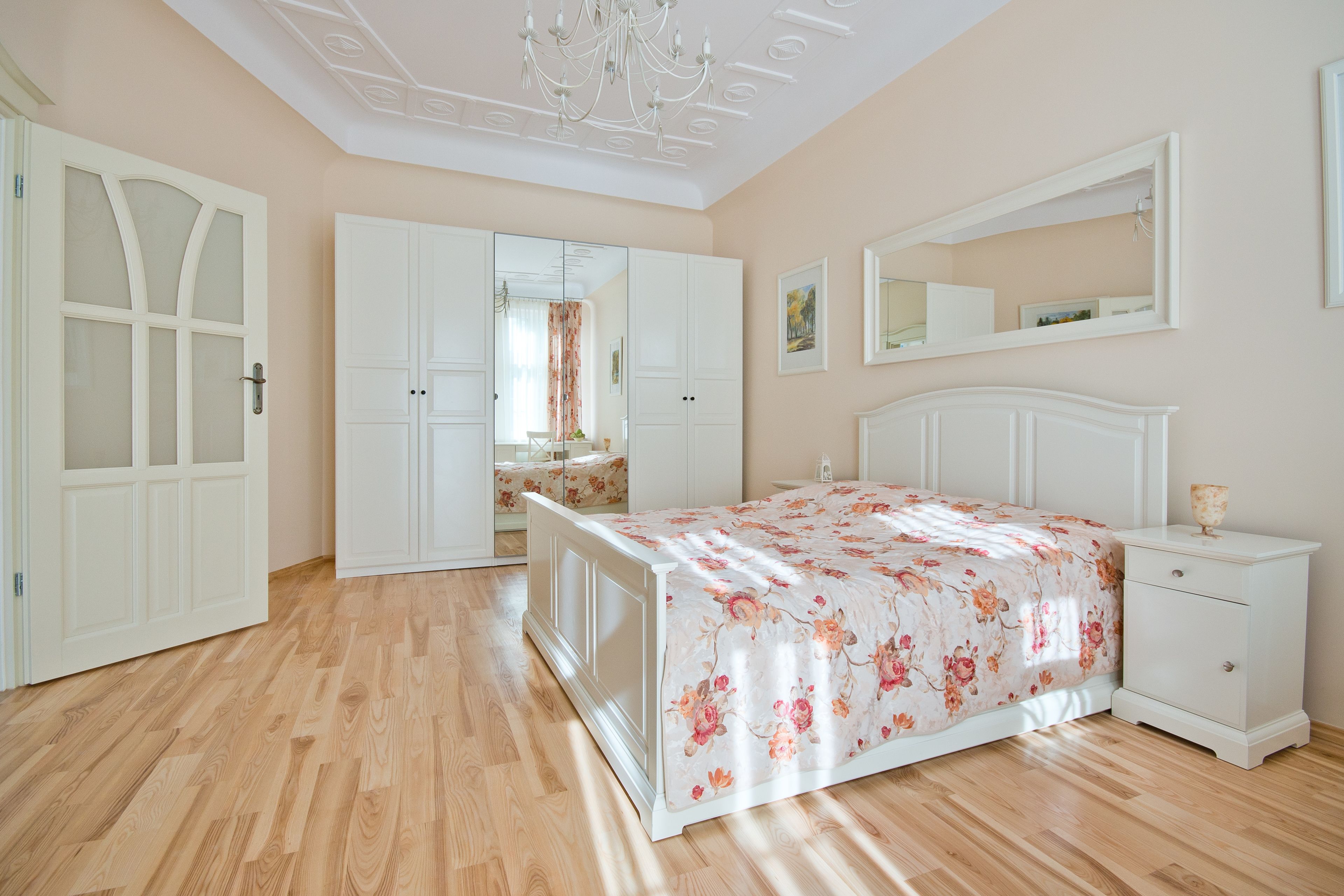 A bedroom with a bed, a dresser, a mirror, and a wardrobe.