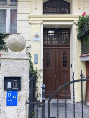 Un edificio con una puerta doble marrón, barandilla de piedra y buzón.