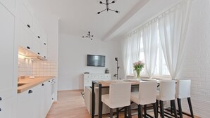 Una cocina moderna con armarios blancos, encimera de madera y un comedor con mesa y sillas.