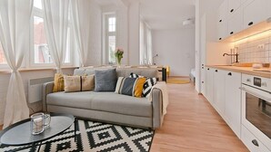 Un apartamento moderno con una sala de estar que incluye un sofá, una mesa de centro y una alfombra estampada.