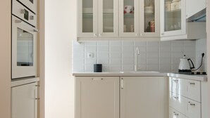 Una cocina moderna con armarios blancos, horno integrado y lámpara de araña.