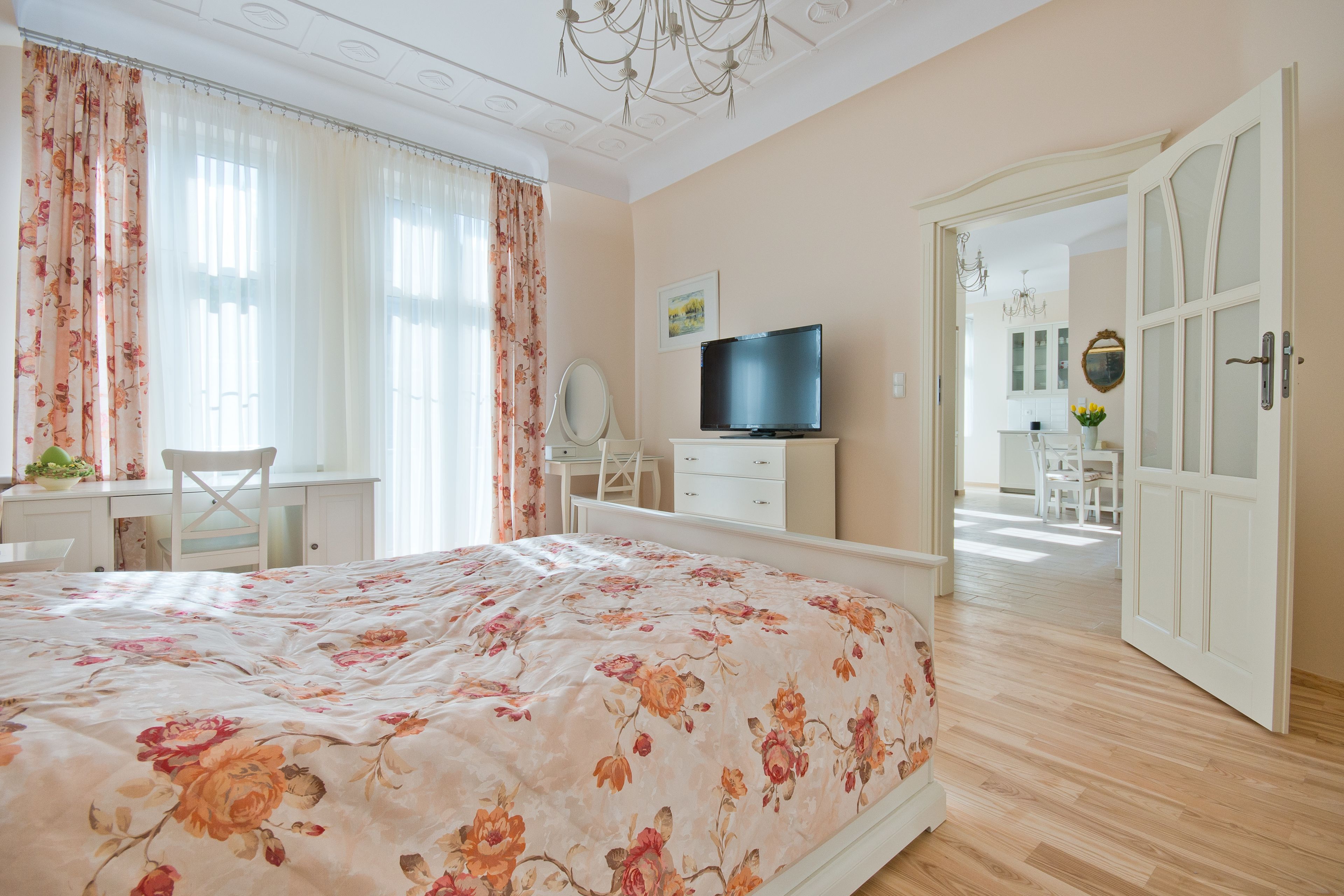 Een slaapkamer met een groot bed, een televisie, een bureau met stoel, en een badkamer zichtbaar door een geopende deur.