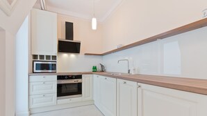 A modern kitchen with white cabinetry, a built-in microwave, an oven, and a wooden countertop.