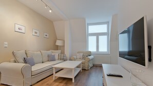 A modern living room with a sofa, a coffee table, a TV, and a lamp.