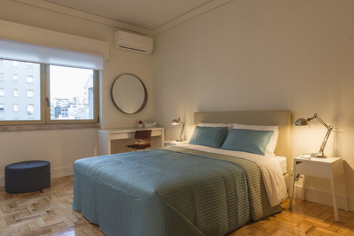 A bedroom with a bed, bedside tables, a desk, and a chair.