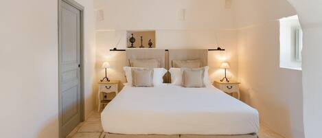 Une chambre à coucher avec un grand lit, deux tables de chevet et une petite table de nuit.
