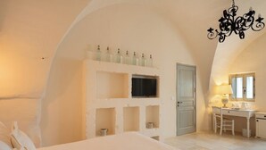 Un dormitorio con cama, escritorio, silla, televisor y candelabro.