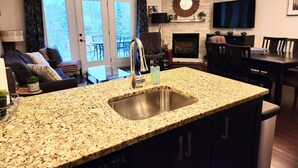 Una cocina con encimeras de granito, un lavamanos de acero inoxidable y un comedor con chimenea.