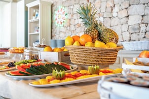 A buffet table with a variety of fruits and a stone wall in the background.