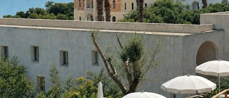 A pool area with a view of a Mediterranean-style building and the sea.