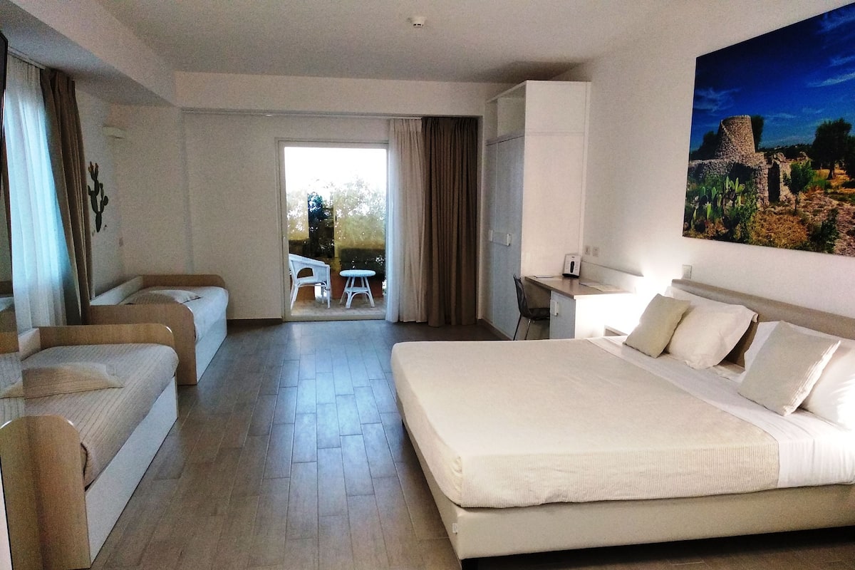 Ein Hotelzimmer mit einem großen Bett, einem Schreibtisch und Blick ins Freie.