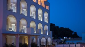 A modern building with multiple arched windows and balconies, featuring a spacious entrance and a well-lit facade. - Est Hotel (Santa Cesarea Terme)