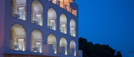 A modern building with multiple arched windows and balconies, featuring a spacious entrance and a well-lit facade.