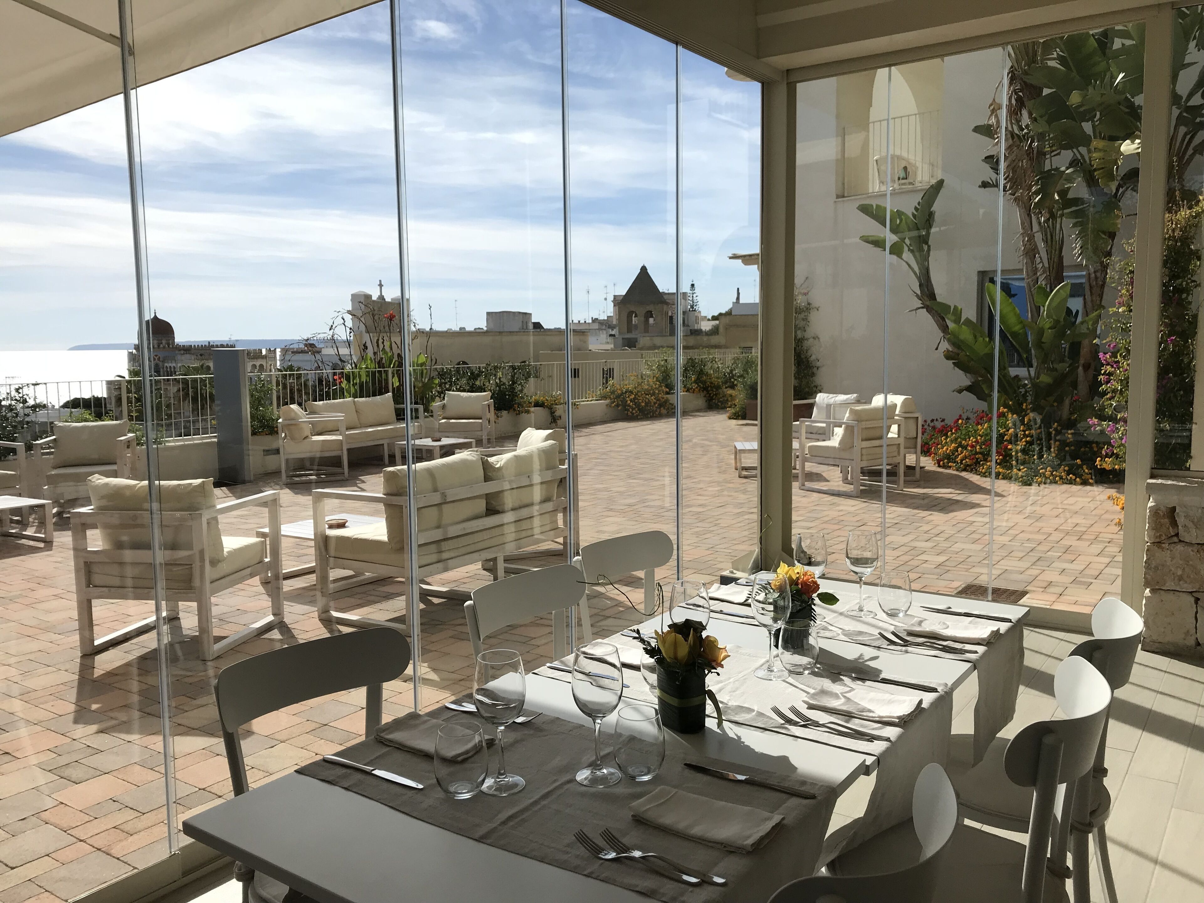 Ein Dachterrasse-Essbereich mit Tischen für zwei Personen, mit Blick auf Stadt und Meer.