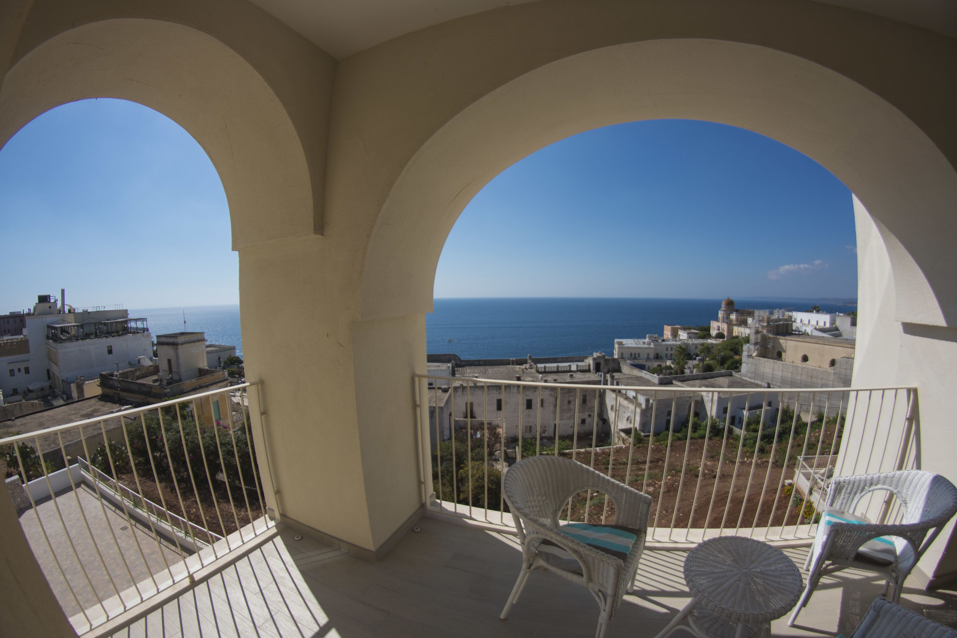 A balcony with a view of the sea and buildings.