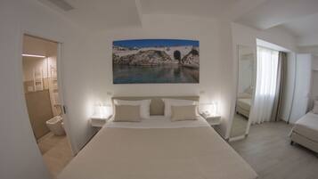 Ein geräumiges Schlafzimmer mit einem großen Bett, Nachttischen und einem Gemälde einer Brücke über dem Wasser.