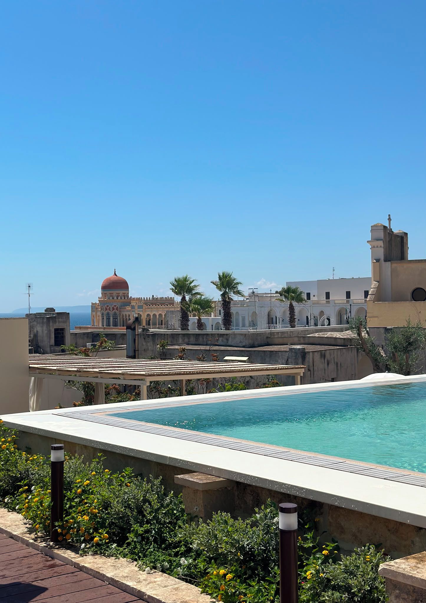 Una piscina en la azotea con vistas despejadas a un edificio histórico con cúpula y arcos al fondo.