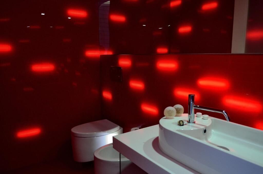 Une salle de bain moderne avec un lavabo blanc, des toilettes et un miroir.