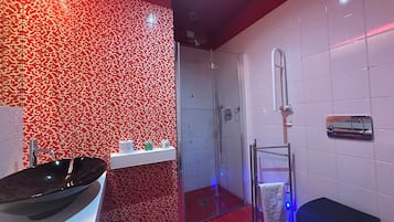 Een moderne badkamer met een zwarte wastafel, een glazen douchecabine en een witte betegelde wand met een rood patroon.