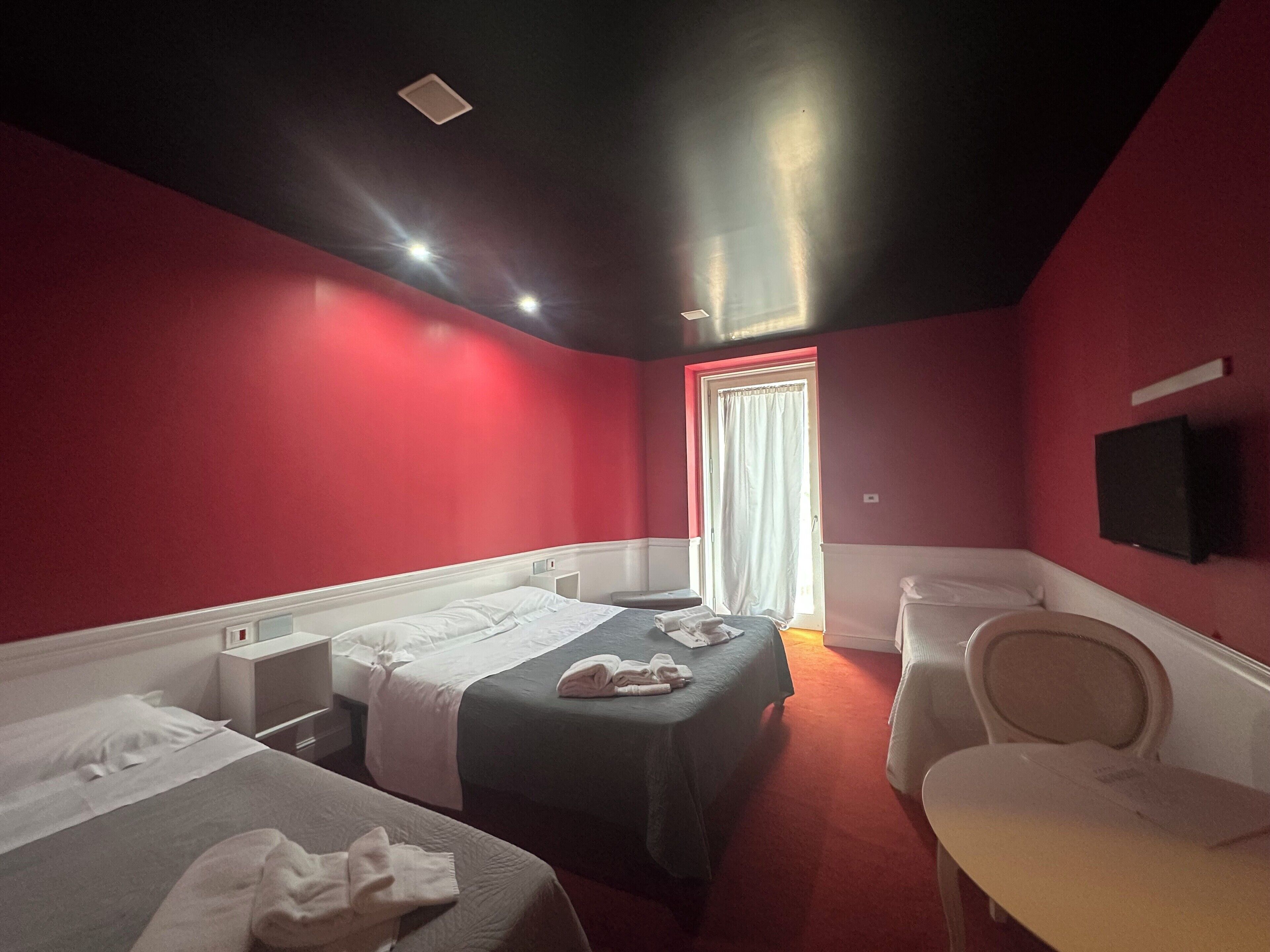 Una habitación de hotel con dos camas, un escritorio, una silla y un televisor en la pared.