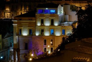 Um edifício com várias andares, com varandas e janelas iluminadas à noite.