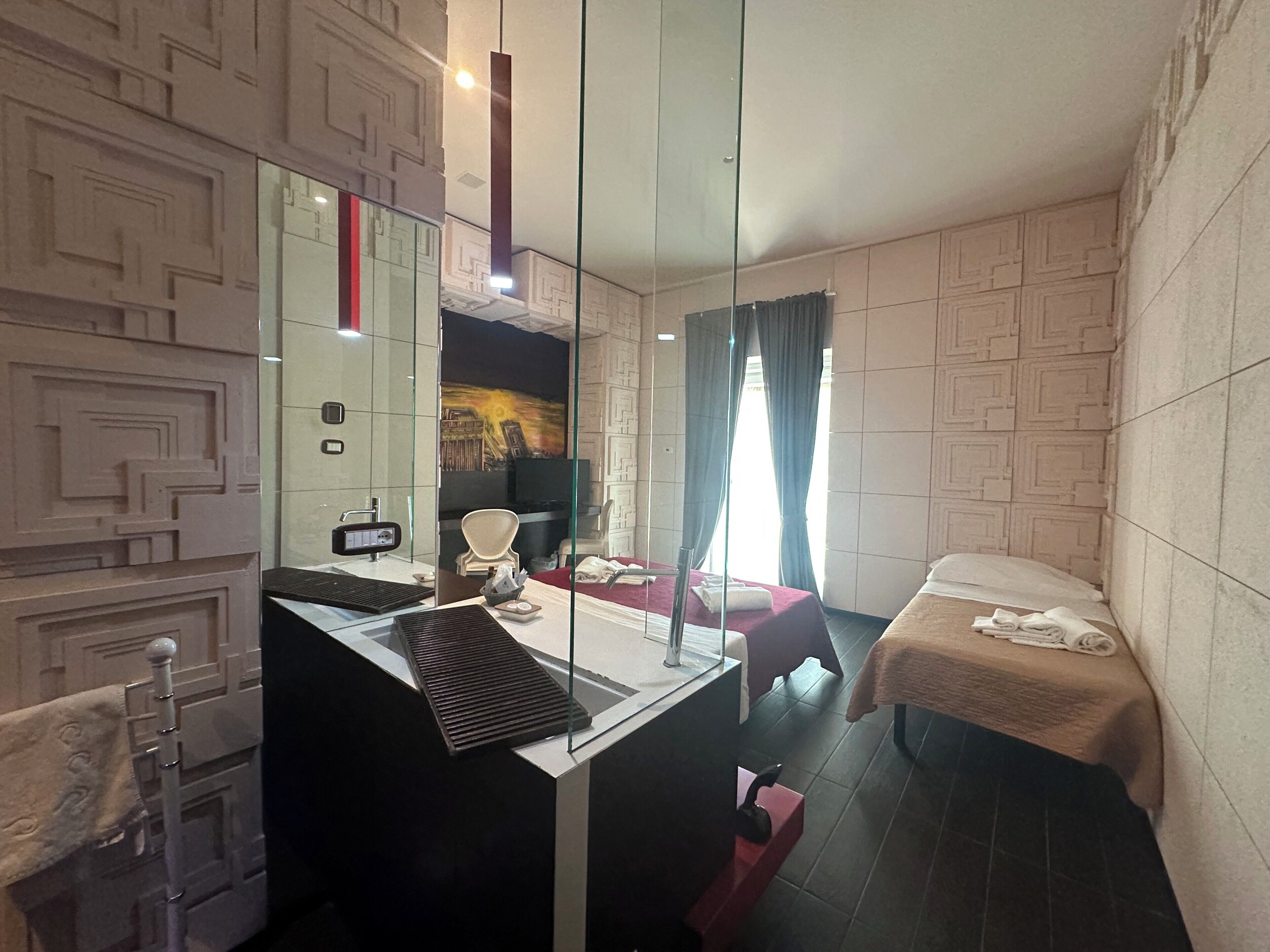 Una habitación de hotel moderna con un espejo grande, un escritorio, una cama y una pequeña zona de estar.