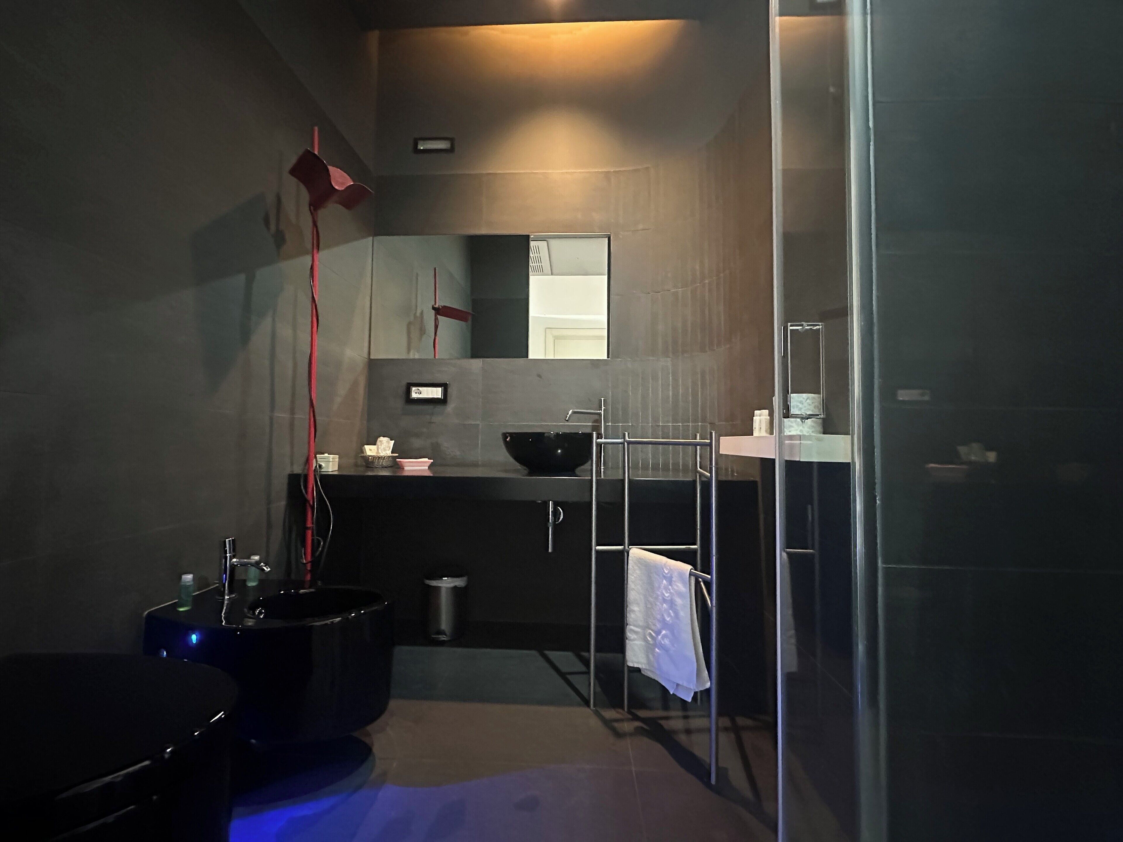 A modern bathroom with a black sink, a large mirror, and a glass shower enclosure.