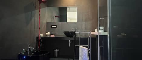 A modern bathroom with a black sink, a large mirror, and a glass shower enclosure.