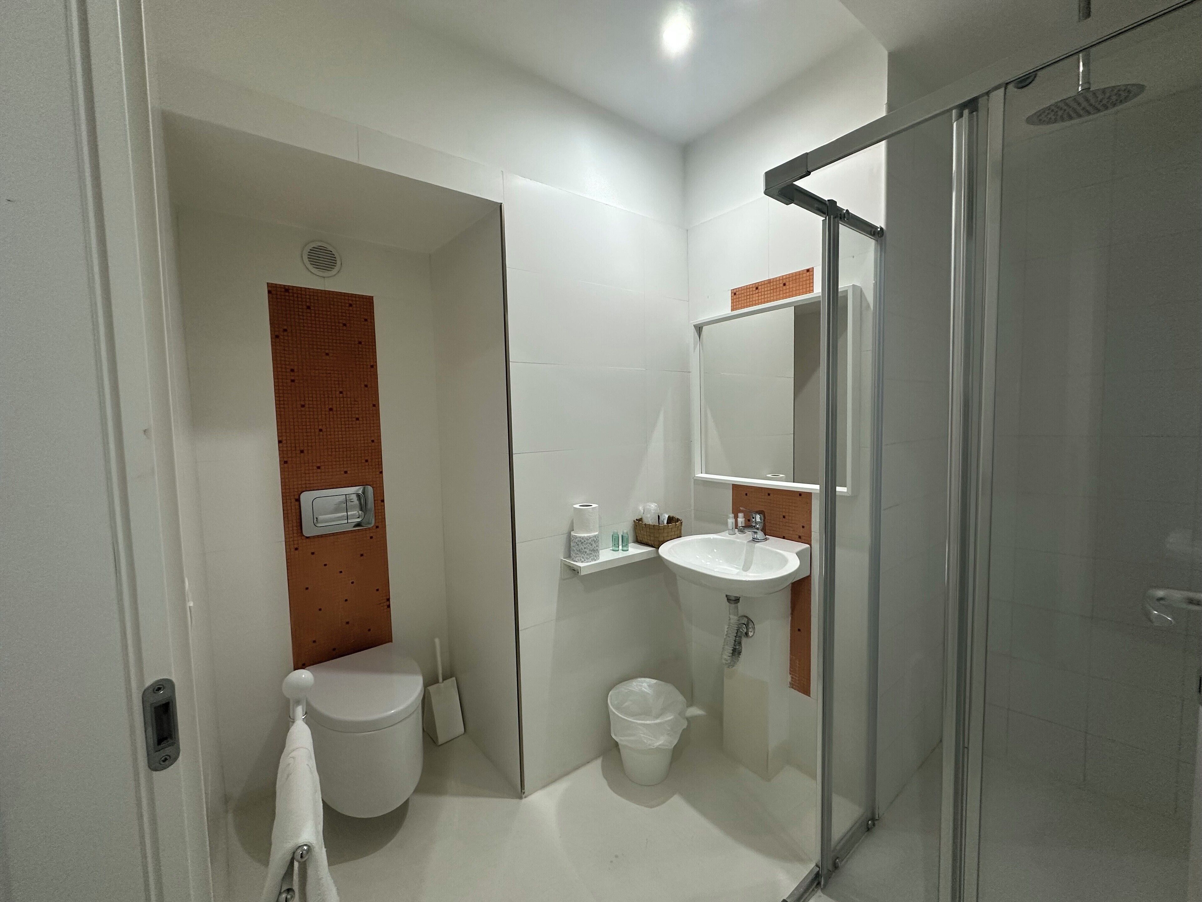 A modern bathroom with a toilet, sink, and shower.