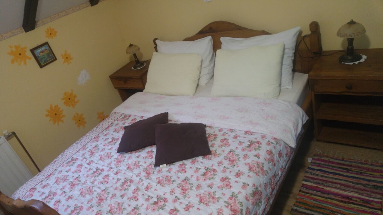 Un lit avec une literie à motifs floraux, deux tables de chevet avec des lampes et un mur décoré de tournesols.