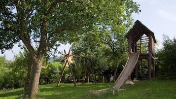 Children can play on the slide and climb in this shaded park area surrounded by mature trees.