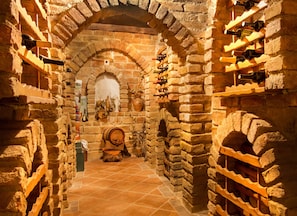 A narrow stone-walled cellar with wooden wine racks and a large barrel. - Stara Vodenica (Klanjec)