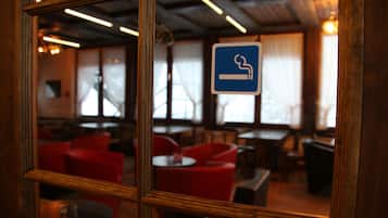 A restaurant interior with red chairs, tables, and a blue smoking sign.