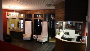 Een hotel lobby met twee witte fauteuils, een receptiebalie en een kroonluchter.