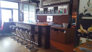 Een bar met krukken, een toonbank vol flessen, en een Coca-Cola bord.