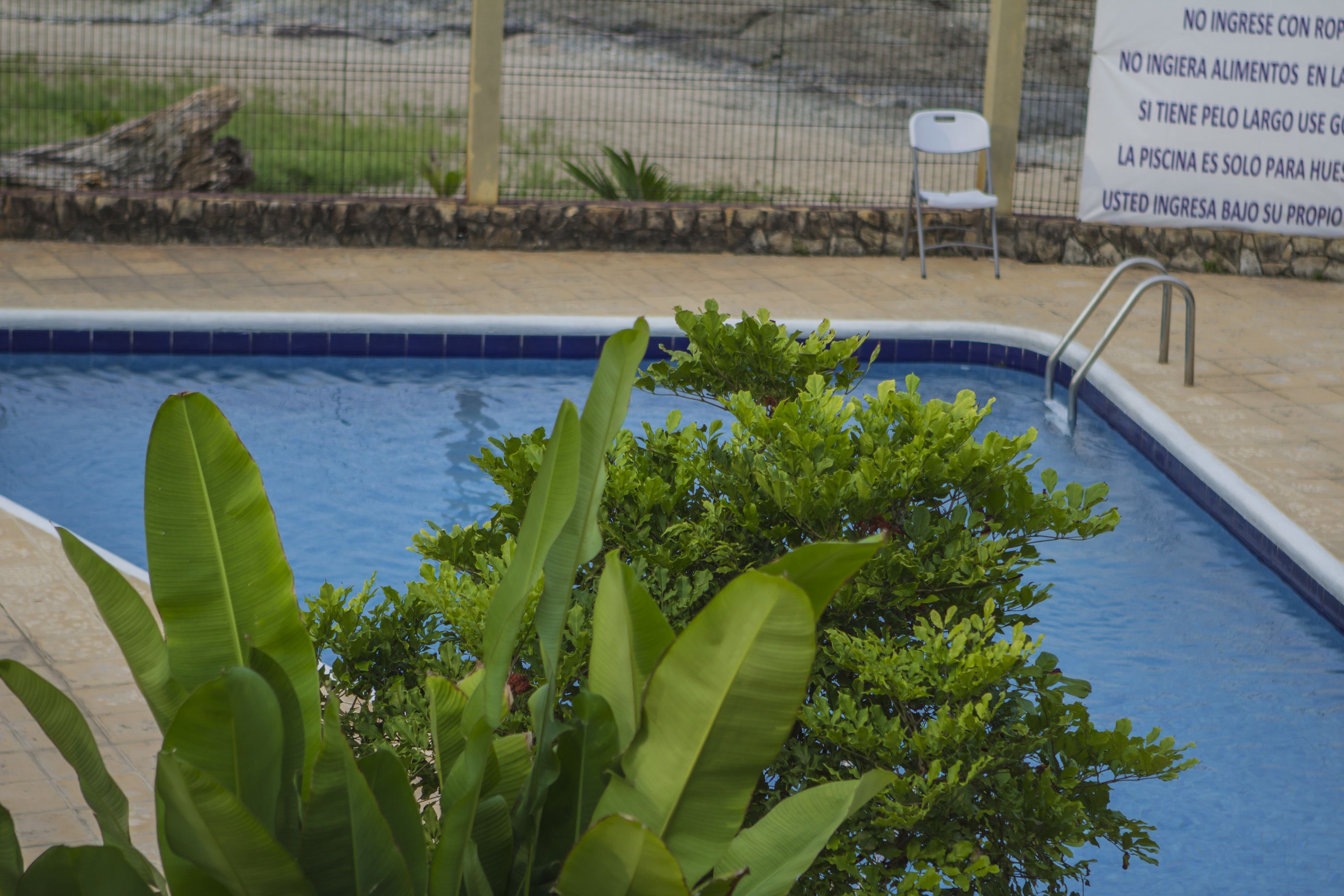 A swimming pool with a metal ladder and a sign in Spanish.