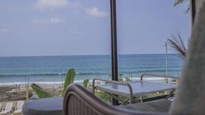Blick auf den Strand durch ein Fenster von einem Zimmer aus, das auf den Ozean hinausblickt.