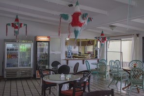 A restaurant interior with tables and chairs, a refrigerator, and a counter.