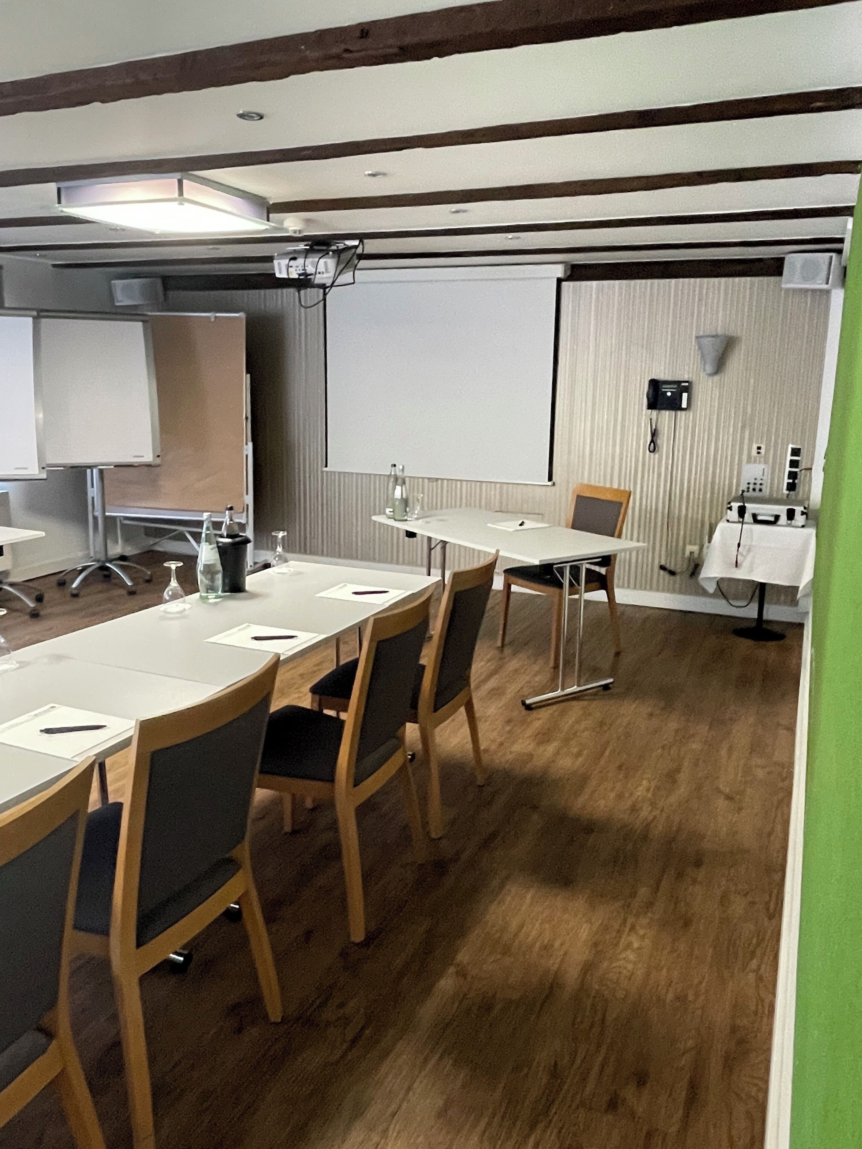 A conference room with a long table, chairs, a projector, a whiteboard, and a telephone.