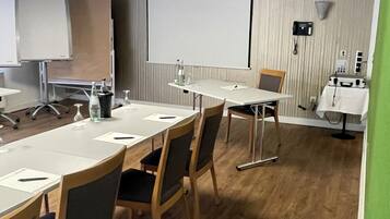 A conference room with a long table, chairs, a projector, a whiteboard, and a telephone.